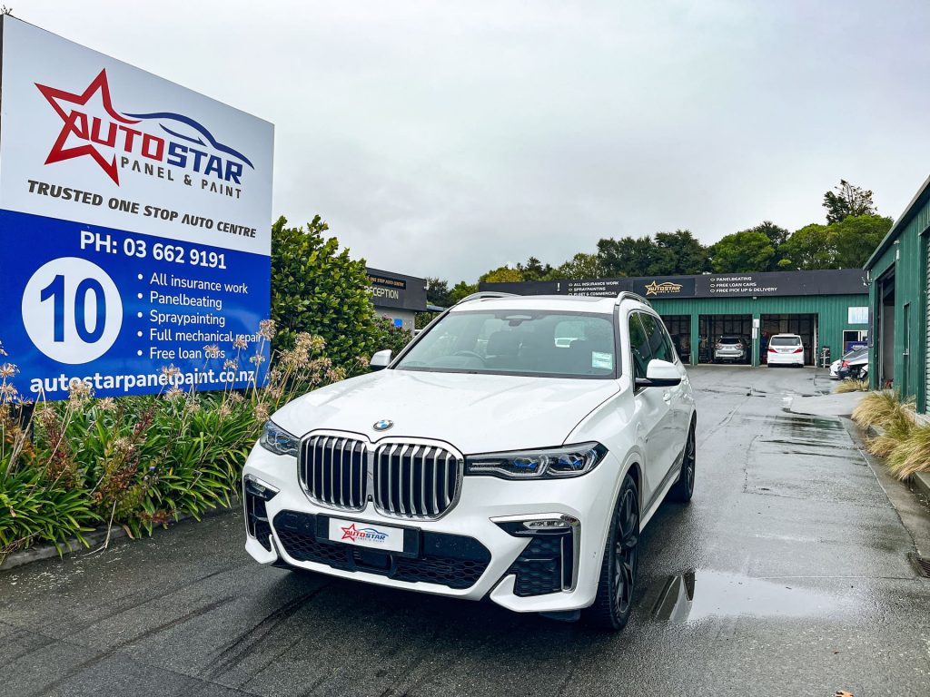 A white luxury BMW SUV parked outside Autostar Panel & Paint, demonstrating their expert collision repair and spray painting finish.